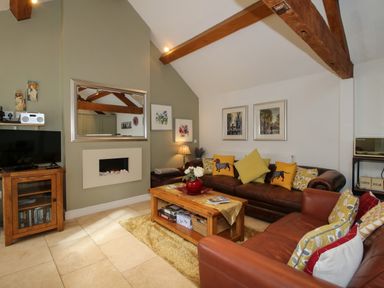 A living room with brown leather sofas wooden coffee table and wall mirror at The Milking Parlour in Yarpole near Leominster