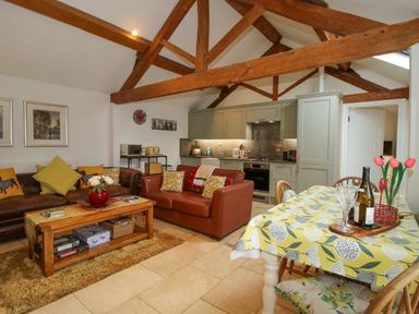 An open plan living area with sofas coffee table kitchen and dining table at The Milking Parlour in Yarpole near Leominster