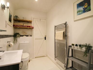 A bathroom with a sink toilet shelves towels plants and a heated towel rail at The Milking Parlour Yarpole near Leominster