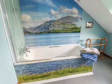 A bathroom with a bathtub and a waterfall mural at Glan y Gors in Dinorwic near Llanberis