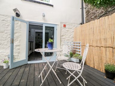A patio with metal table and chairs and potted plants outside doors at The Old Dairy Maker near Millbrook