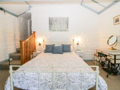 A bedroom with a bed pillows bedside tables wall lamps and a dressing table at The Old Dairy Maker near Millbrook