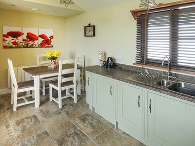 A kitchen with a dining table and chairs a sink and a window with blinds at Black Mountain View in Llanafan Fawr near Builth Wells