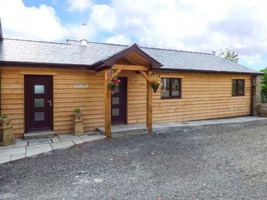 A wooden exterior of a building with two dark doors and windows at Black Mountain View in Llanafan Fawr near Builth Wells