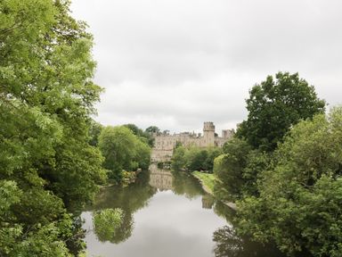 A river surrounded by trees with a castle in the background at 24 College Lane in Stratford-Upon-Avon