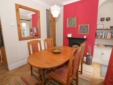 A dining room with wooden table and chairs a mirror on the wall a fireplace with candles and artwork bookshelf and a rug at 24 College Lane in Stratford-Upon-Avon