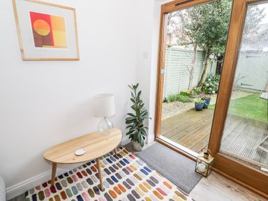 A room corner with a wooden coffee table a table lamp a potted plant and sliding glass doors leading to a garden at 24 College Lane Stratford-Upon-Avon