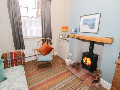 A small sitting room with a wood-burning stove chair and cabinet at 24 College Lane in Stratford-Upon-Avon