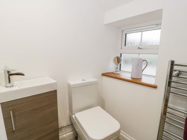 A bathroom with a toilet sink cabinet window and towel rack at Ty'n Lon Bach in Llandwrog