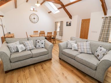 A living room with two sofas and dining table with chairs at Ty'n Lon Bach in Llandwrog