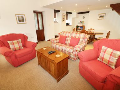 A living room with red armchairs a plaid sofa and a wooden coffee table at Kingfisher Barn in Staveley near Windermere