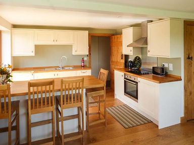 A kitchen with wooden countertops and chairs and a stove at Glebe Farm Cottage in Llandegveth near Cwmbran