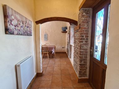 A hallway with tiled floor a wooden arch and a dining area with table and chairs at Swallow Cottage in Llanboidy