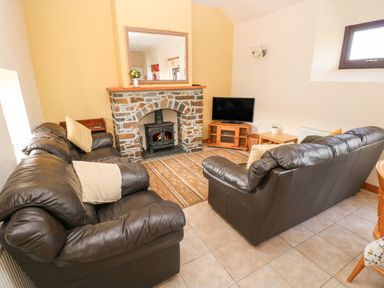 A living room with leather sofas a stone fireplace and a television at Hill Top Farm Cottage in Martletwy near Narbeth