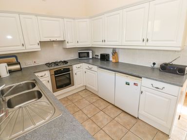A kitchen with white cabinets a stainless steel double sink an oven a microwave a toaster and a radio at Hill Top Farm Cottage Martletwy near Narbeth