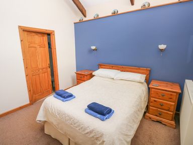 A bedroom with a double bed between two wooden nightstands and a blue painted wall at Hill Top Farm Cottage Martletwy near Narbeth
