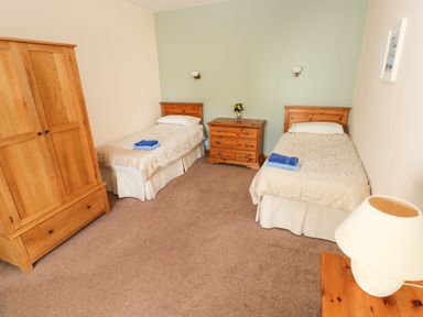 A bedroom with two single beds wooden furniture and a lamp at Hill Top Farm Cottage Martletwy near Narbeth