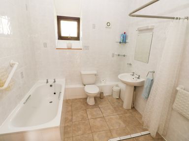 A bathroom with a bathtub toilet sink mirror and tiled floor at Hill Top Farm Cottage Martletwy near Narbeth