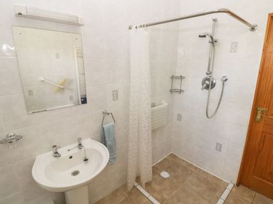A bathroom with a pedestal sink mirror towel rack and walk in shower with curtain at Hill Top Farm Cottage Martletwy near Narbeth