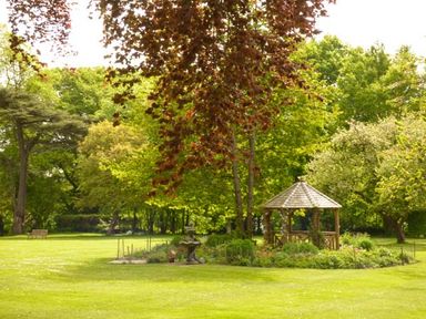 A garden with a wooden gazebo and trees at Beech View in Malton