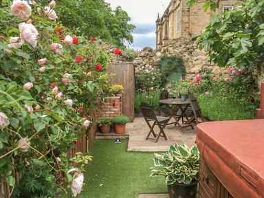 A garden with wooden chairs and table surrounded by flowers and plants at Beech View in Malton