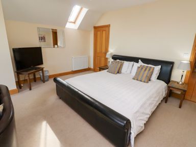 A bedroom with a bed and TV at Granary Stone House Embleton
