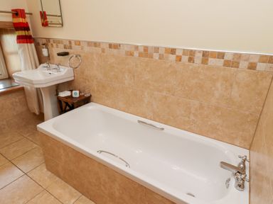 A bathroom with a bathtub and sink at Granary Stone House in Embleton