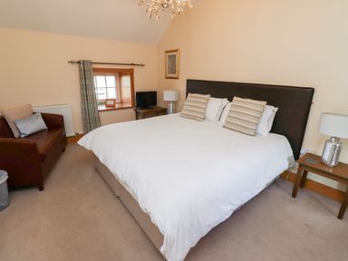 A bedroom with a bed and sofa at Granary Stone House in Embleton