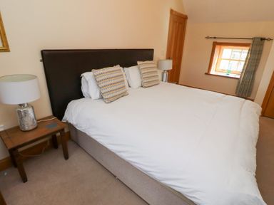 A bedroom with a bed and bedside lamp at Granary Stone House in Embleton