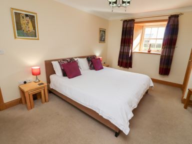 A bedroom with a bed and bedside tables at Granary Stone House in Embleton