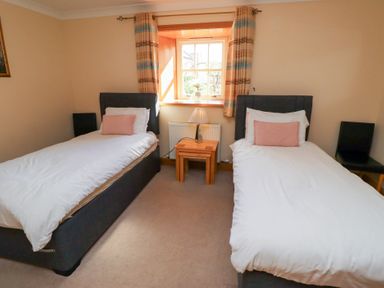 A bedroom with two beds and a table at Granary Stone House Embleton
