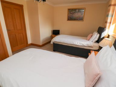 A bedroom with two beds and a television at Granary Stone House in Embleton