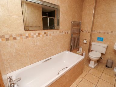 A bathroom with a bathtub and toilet at Granary Stone House in Embleton