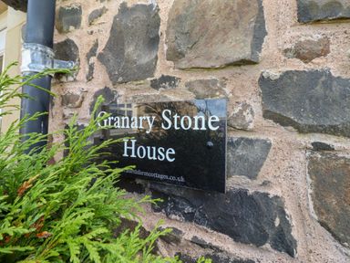 A sign on a stone wall for Granary Stone House in Embleton