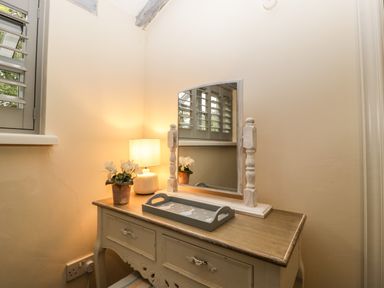 A dressing table with a mirror lamp flower pot and tray at Pear Tree Cottage Mark near Burnham on Sea