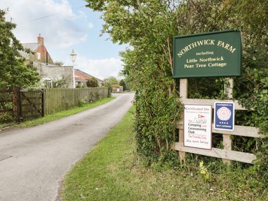 A farm entrance with signs and a driveway at Northwick Farm including Little Northwick Pear Tree Cottage in Mark near Burnham-on-Sea
