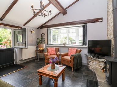 A living room with chairs and a television at Pear Tree Cottage Mark near Burnham-on-Sea