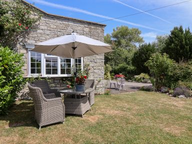 A garden with a table and chairs under an umbrella at Pear Tree Cottage near Burnham-on-Sea
