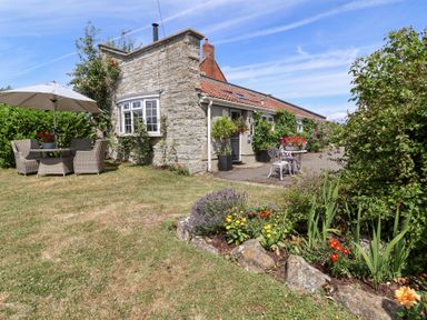 An outdoor area with seating and flowers at Pear Tree Cottage Mark near Burnham-on-Sea