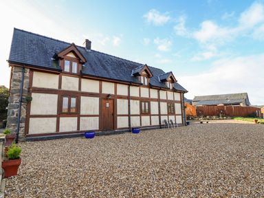 A gravel courtyard in front of a timber framed building with dormer windows and a wooden door at The Old House in Llanidloes