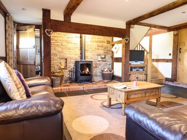 A living room with a wood burning stove coffee table and leather sofas at The Old House in Llanidloes