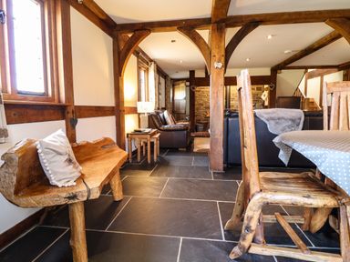 A living room with wooden beams wooden bench and wooden dining chairs at The Old House in Llanidloes