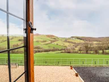 An open window with a view of green hills and trees at The Old House in Llanidloes