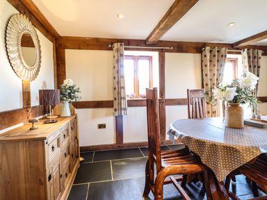 A dining room with a wooden table covered by a polka dot tablecloth and wooden chairs at The Old House in Llanidloes