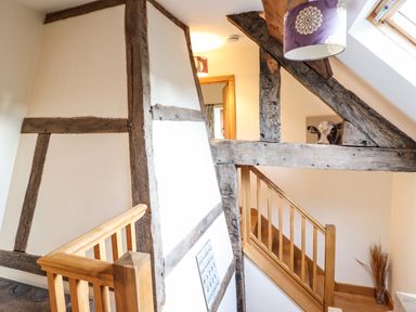 A staircase with wooden railings and exposed wooden beams on walls and ceiling at The Old House in Llanidloes