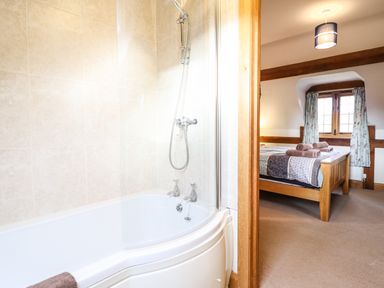 A bathroom with a bathtub and shower next to a bedroom with a wooden bed at The Old House in Llanidloes