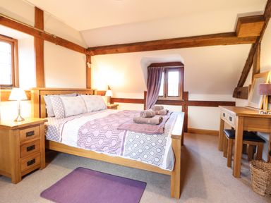 A bedroom with a double bed bedside tables lamps a desk stool and a window at The Old House in Llanidloes