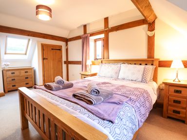 A bedroom with a wooden bed frame bedside tables and a chest of drawers at The Old House in Llanidloes