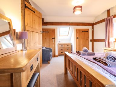 A bedroom with wooden furniture two wooden doors a skylight and rolled towels on the bed at The Old House in Llanidloes