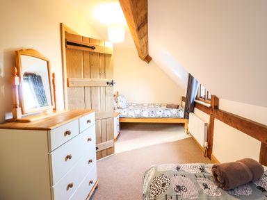 A bedroom with two single beds a chest of drawers and a wooden door at The Old House in Llanidloes